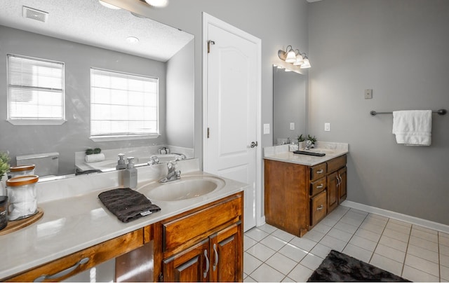 bathroom with tile patterned floors, plenty of natural light, a textured ceiling, and vanity