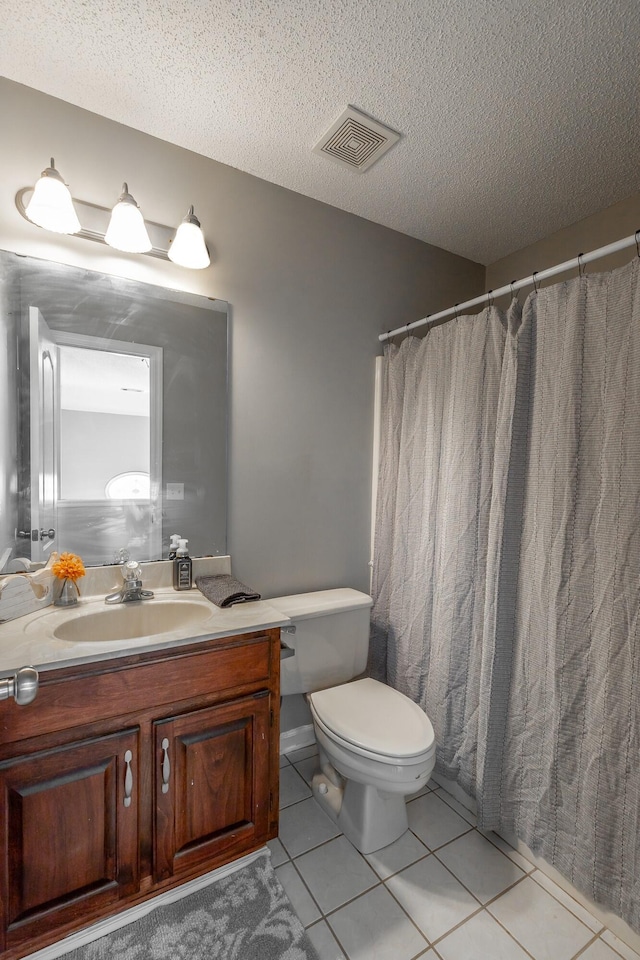 bathroom with tile patterned flooring, vanity, a textured ceiling, and toilet