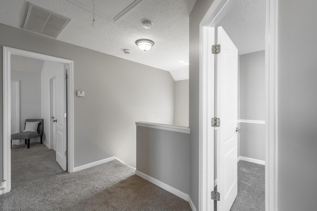 hall with carpet flooring, a textured ceiling, and vaulted ceiling