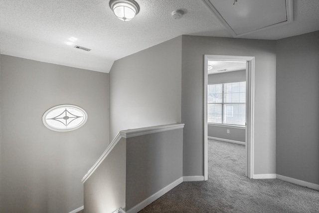 hallway featuring carpet flooring, lofted ceiling, and a textured ceiling