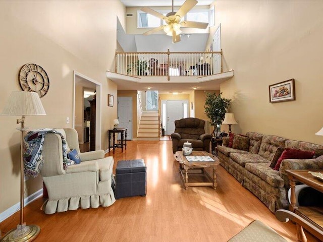 living room featuring a high ceiling, ceiling fan, a healthy amount of sunlight, and hardwood / wood-style floors