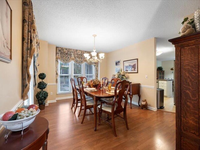 dining room featuring a textured ceiling, dark hardwood / wood-style flooring, and an inviting chandelier