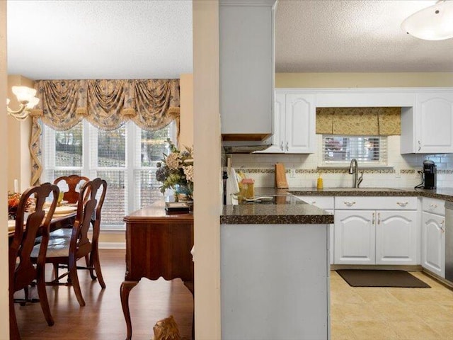 kitchen featuring backsplash, white dishwasher, sink, a textured ceiling, and white cabinetry