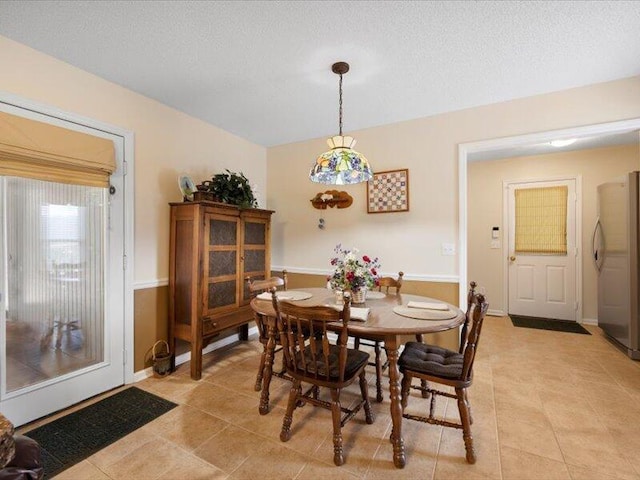 tiled dining room featuring a textured ceiling