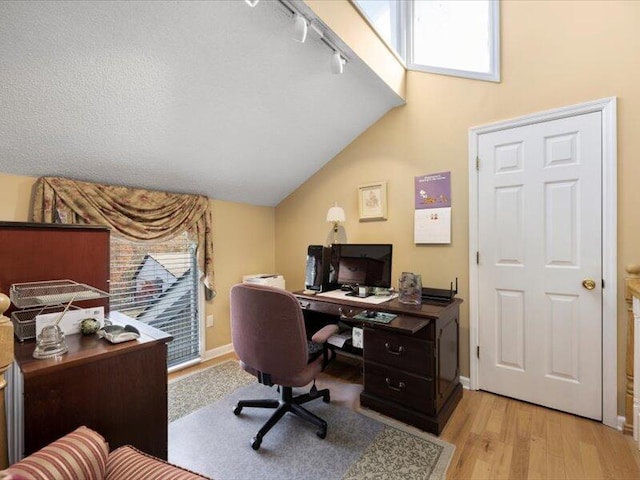 office featuring a textured ceiling, light hardwood / wood-style floors, and vaulted ceiling