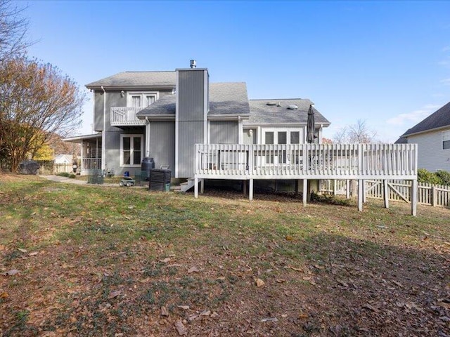 rear view of property featuring a lawn, a balcony, a wooden deck, and central AC