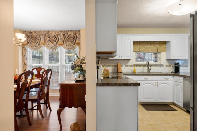 kitchen with a textured ceiling, a sink, white cabinetry, and decorative backsplash