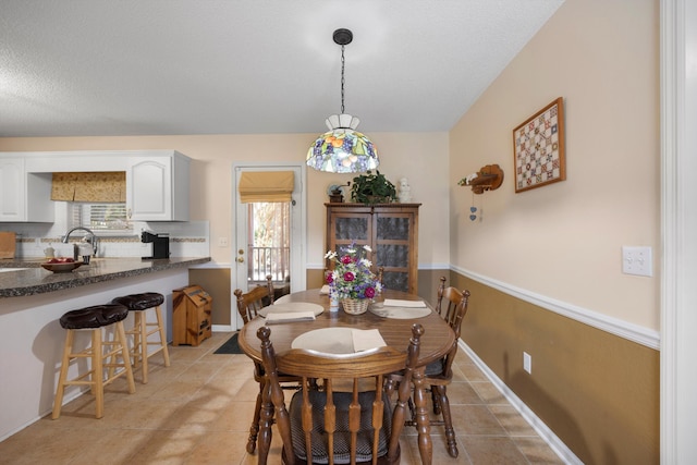 dining room featuring light tile patterned floors, baseboards, and a textured ceiling