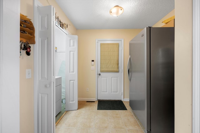 doorway featuring light tile patterned floors, baseboards, and a textured ceiling