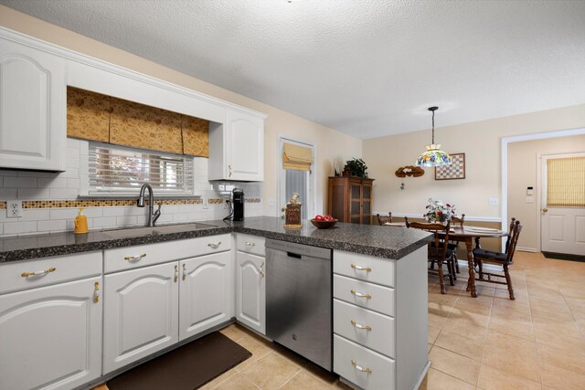 kitchen featuring dishwasher, dark countertops, a peninsula, white cabinetry, and a sink