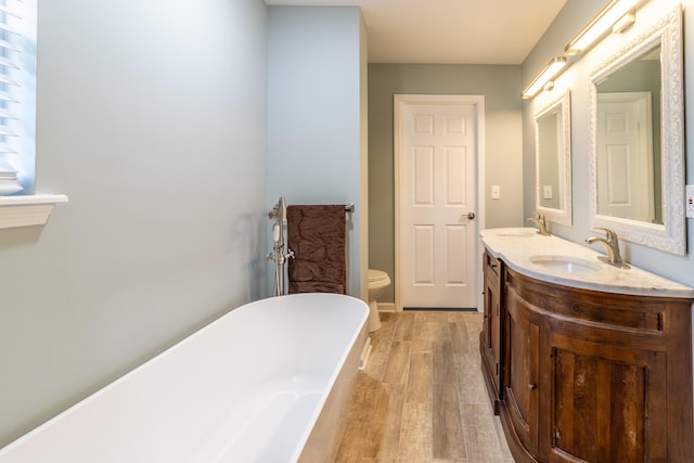 bathroom featuring vanity, toilet, wood-type flooring, and a tub