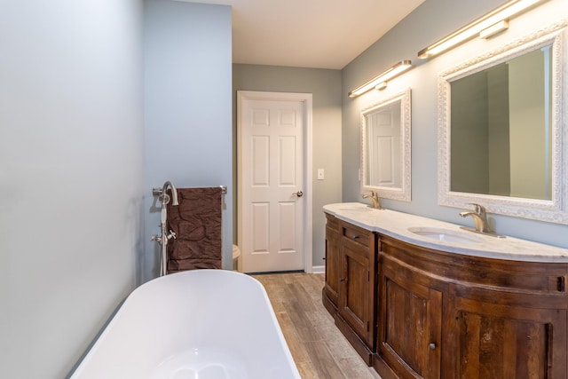 bathroom featuring hardwood / wood-style floors, vanity, and a tub to relax in