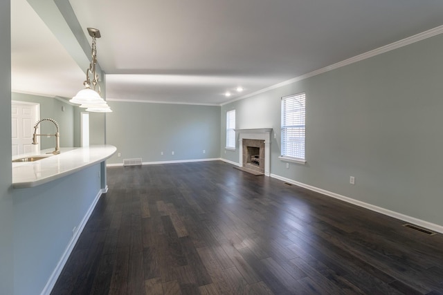 unfurnished living room with dark hardwood / wood-style flooring, crown molding, and sink