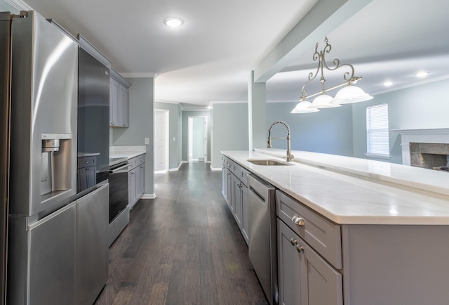 kitchen featuring gray cabinetry, sink, pendant lighting, a center island with sink, and appliances with stainless steel finishes