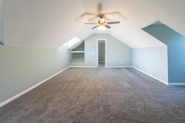 bonus room featuring ceiling fan, dark carpet, built in features, and vaulted ceiling