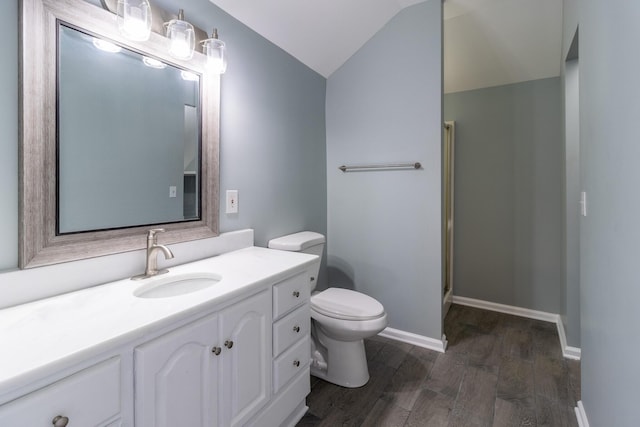 bathroom with vanity, vaulted ceiling, toilet, walk in shower, and wood-type flooring