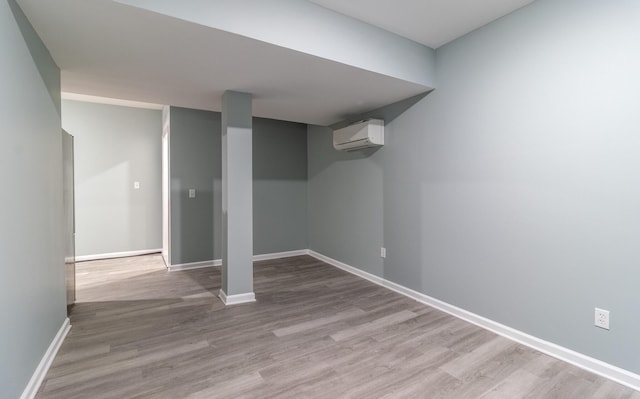 basement with light hardwood / wood-style flooring and an AC wall unit