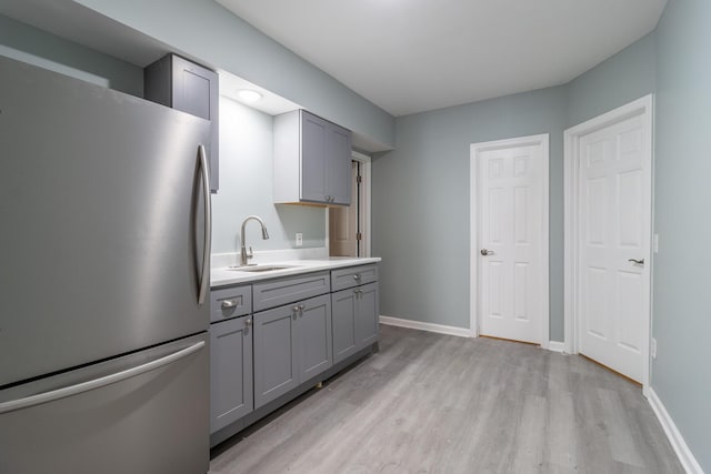 kitchen with light hardwood / wood-style floors, stainless steel refrigerator, gray cabinetry, and sink