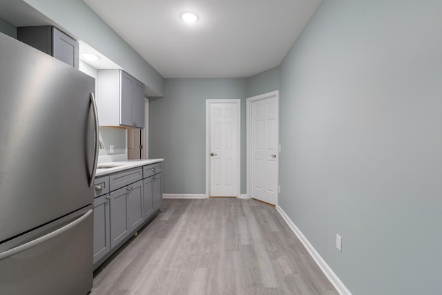 kitchen with gray cabinets, light hardwood / wood-style floors, and stainless steel refrigerator