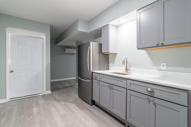 kitchen with stainless steel fridge, gray cabinets, light hardwood / wood-style floors, and sink