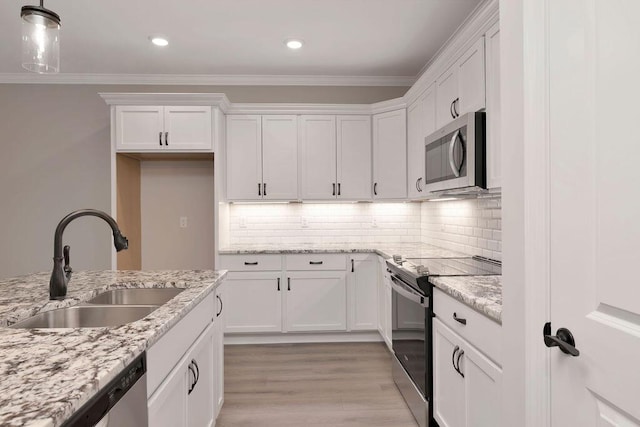 kitchen featuring stainless steel appliances, decorative light fixtures, and white cabinetry