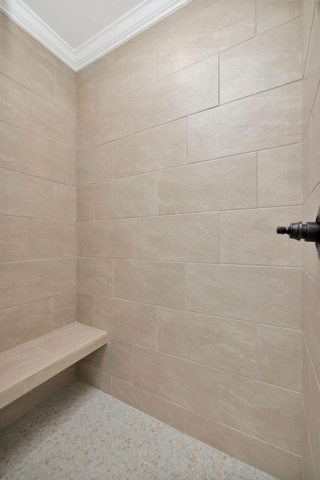 bathroom with a tile shower and crown molding