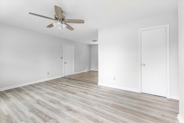 spare room featuring light wood-style floors, ceiling fan, and baseboards