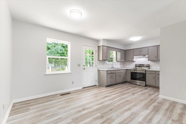 kitchen with stainless steel range with electric stovetop, gray cabinetry, under cabinet range hood, light countertops, and a textured ceiling