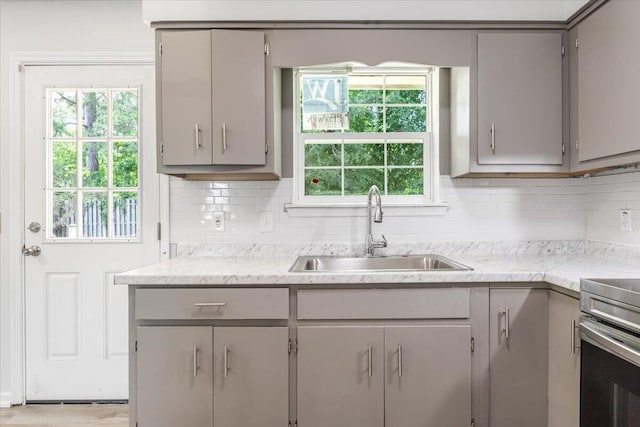 kitchen with gray cabinetry, a sink, tasteful backsplash, and plenty of natural light