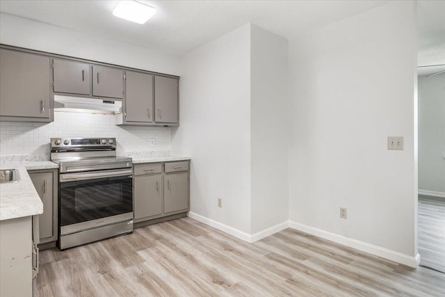 kitchen with stainless steel range with electric stovetop, under cabinet range hood, gray cabinetry, and light wood-style floors