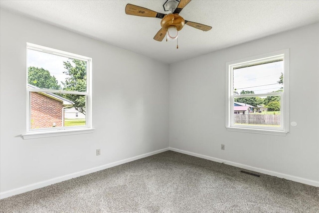 carpeted empty room featuring plenty of natural light, baseboards, and a ceiling fan
