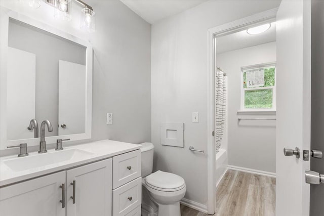 full bath with wood finished floors, toilet, vanity, and shower / bath combo