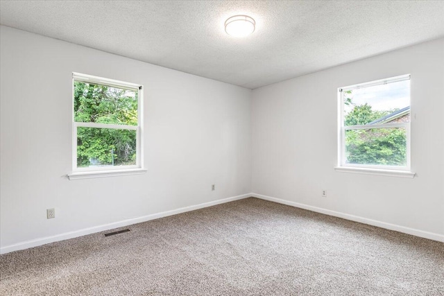 carpeted spare room featuring a textured ceiling and baseboards