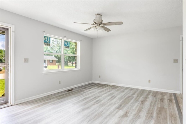 empty room with light wood-style flooring, a ceiling fan, baseboards, and a textured ceiling