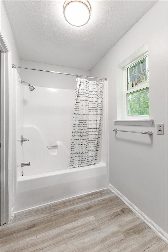 full bathroom featuring shower / bath combo with shower curtain, a textured ceiling, wood finished floors, and baseboards