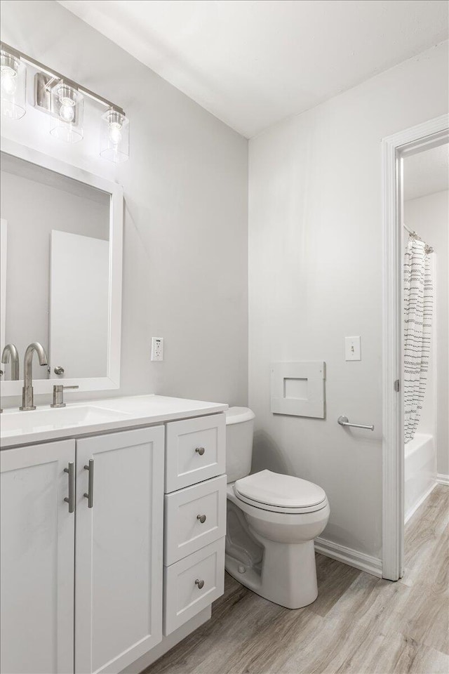 bathroom with wood finished floors, toilet, vanity, and shower / tub combo with curtain