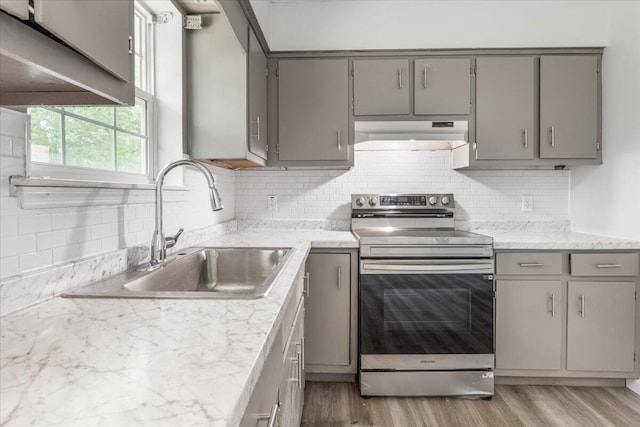 kitchen featuring gray cabinetry, electric stove, a sink, under cabinet range hood, and light wood-style flooring
