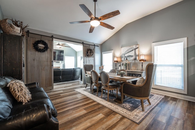 dining area featuring lofted ceiling, a barn door, wood-type flooring, and ceiling fan