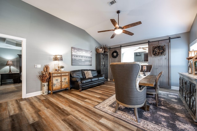 living room with lofted ceiling, a barn door, and wood-type flooring