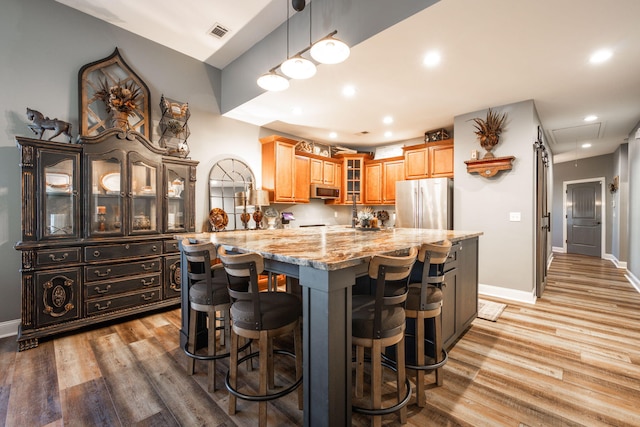 kitchen featuring light stone countertops, a kitchen island, stainless steel appliances, and light hardwood / wood-style floors