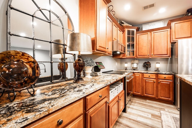 kitchen with electric range, light stone countertops, range hood, and light wood-type flooring