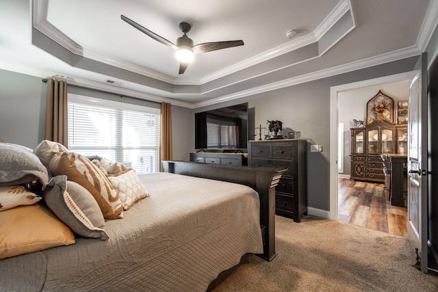 bedroom featuring wood-type flooring, a raised ceiling, ceiling fan, and crown molding