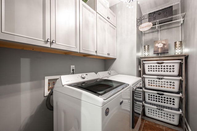 clothes washing area featuring cabinets, a notable chandelier, and washing machine and clothes dryer