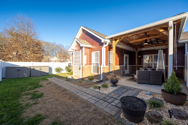 rear view of property featuring outdoor lounge area, ceiling fan, a patio area, and a lawn