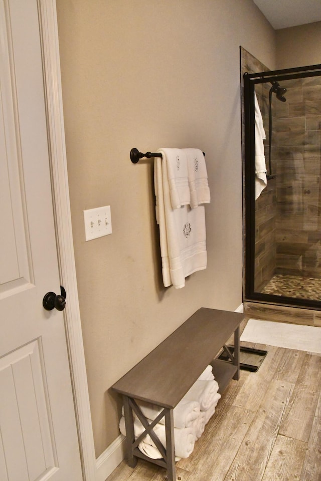 bathroom with a shower with door and hardwood / wood-style floors