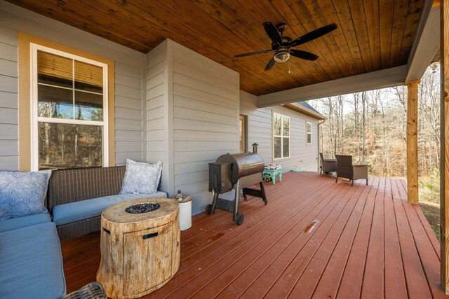 wooden terrace featuring grilling area, ceiling fan, and an outdoor living space with a fire pit