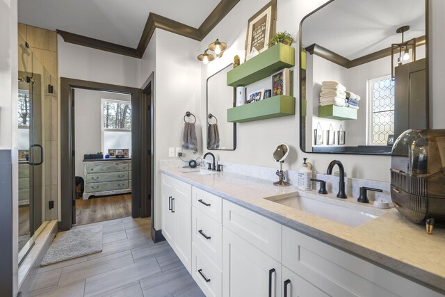 bathroom featuring vanity, a shower with door, and crown molding