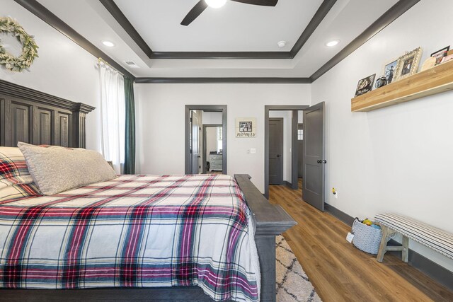 bedroom with a raised ceiling, ceiling fan, and dark hardwood / wood-style floors