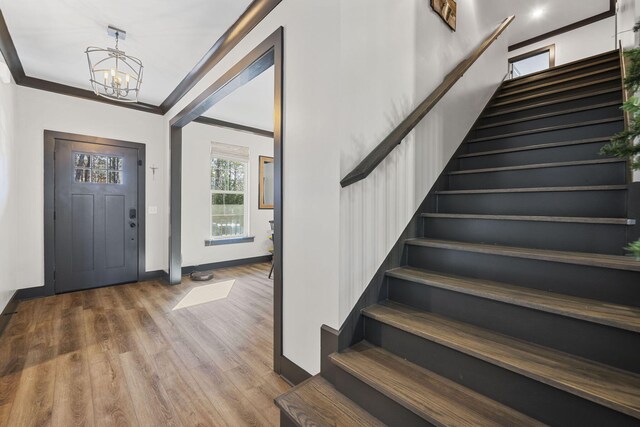 foyer featuring crown molding, hardwood / wood-style floors, and a notable chandelier