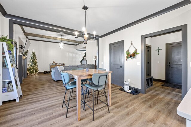 dining space featuring a chandelier, hardwood / wood-style flooring, and beamed ceiling